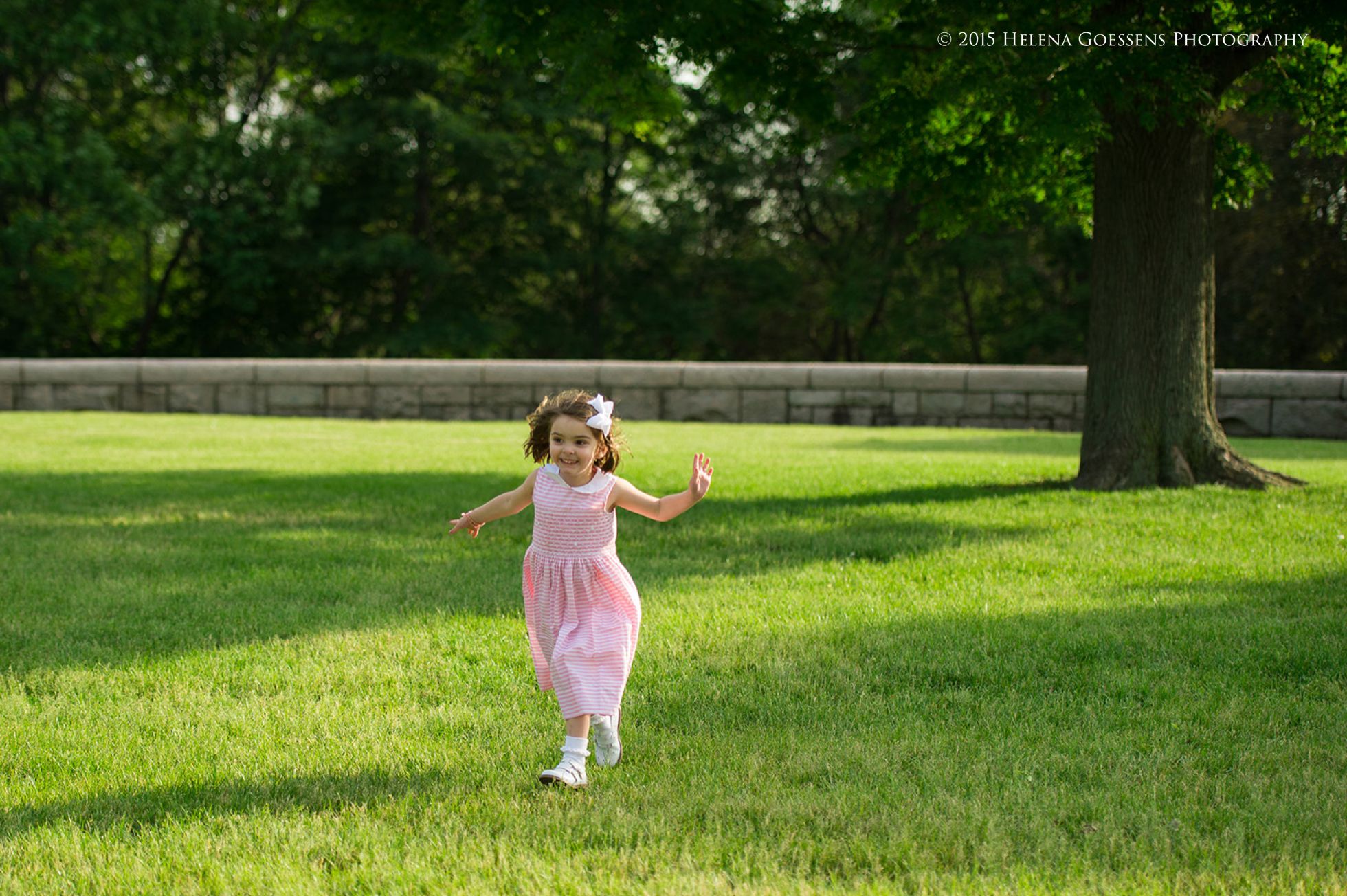 little girl with a pink  dress running at the park