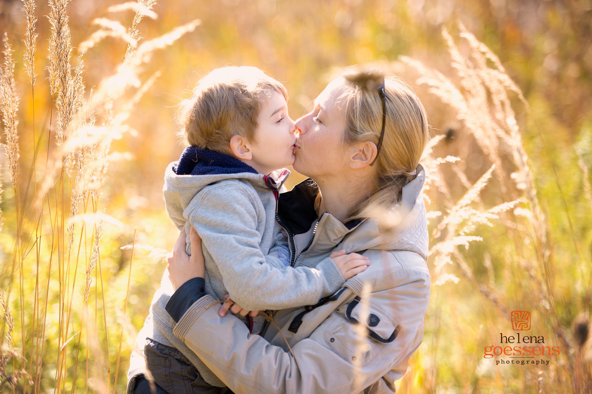 Mother and son kissing at a tall grass field