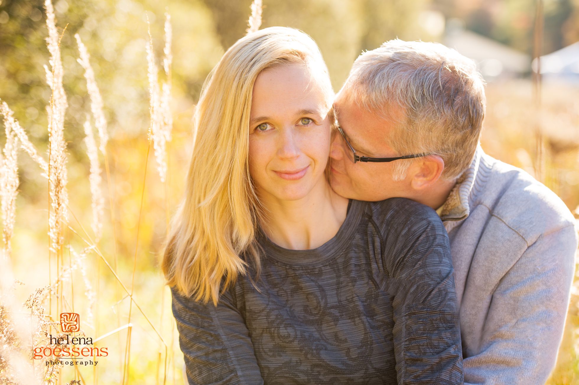 blond woman in a grey sweater being hold by her husband