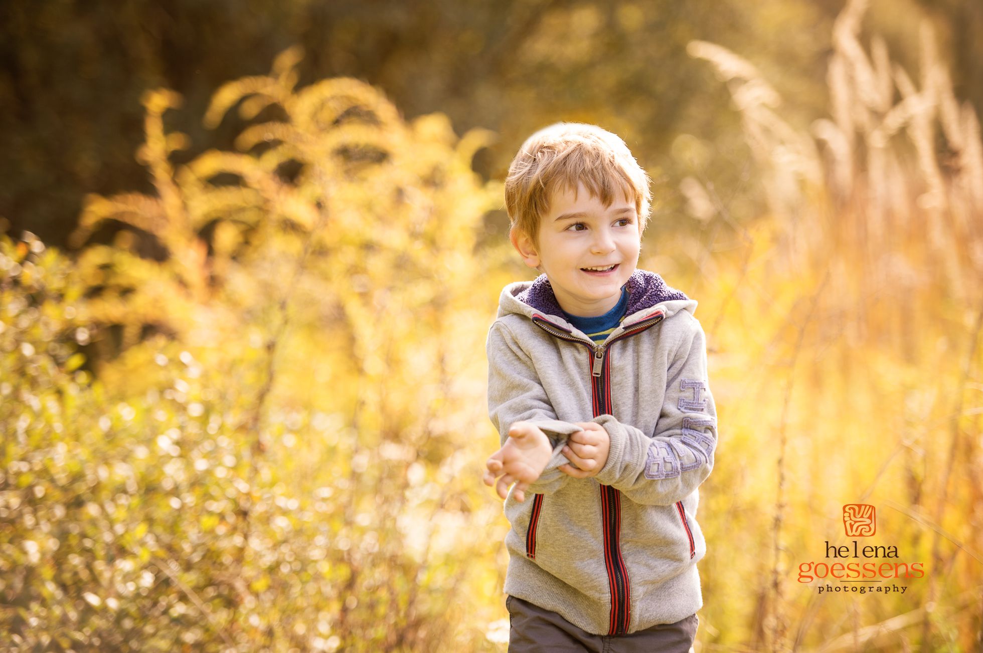 Little boy wearing a grey jacket in a tall grass field. Fall family portrait sessions