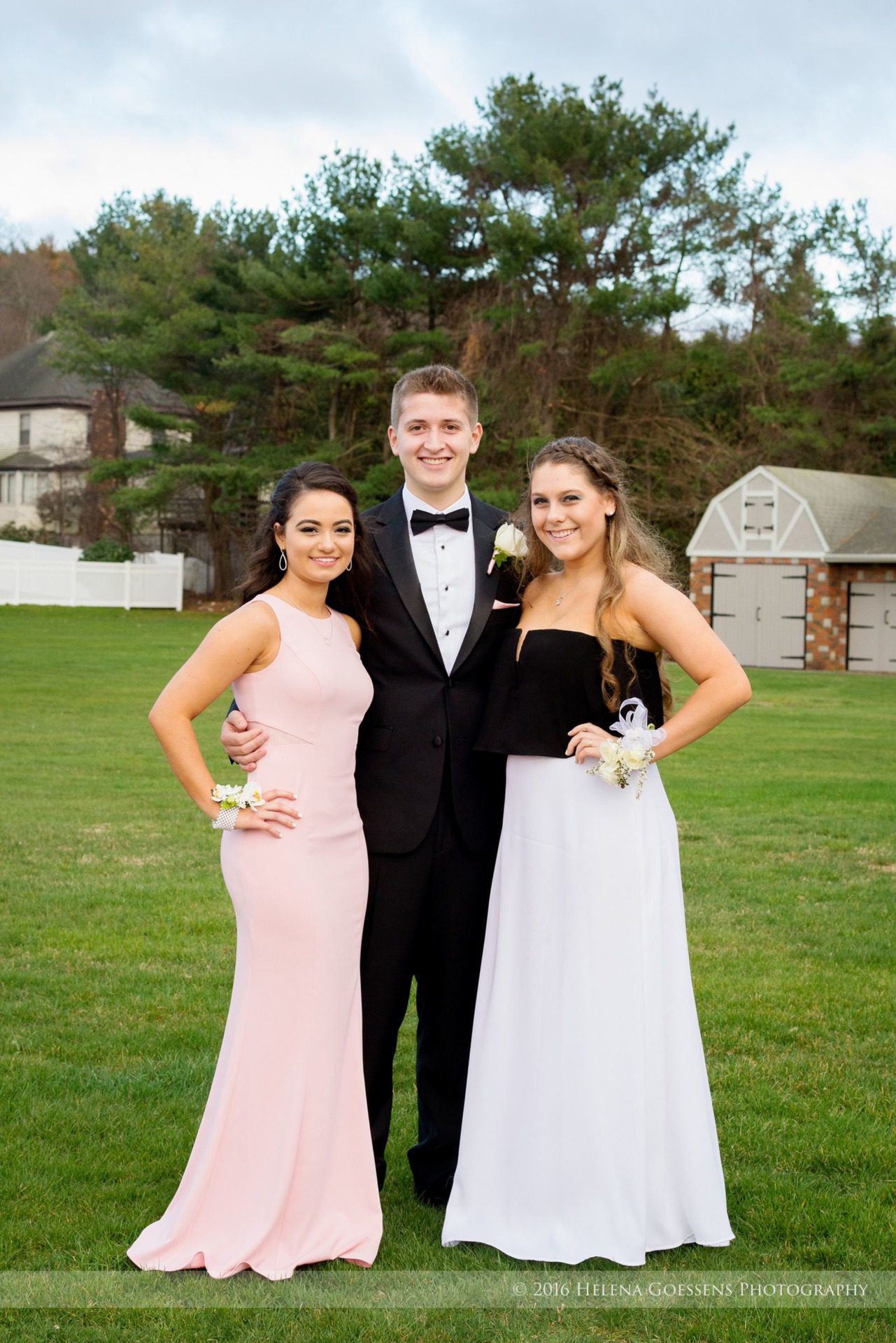 A boy and two girls wearing prom dresses and a tuxedo