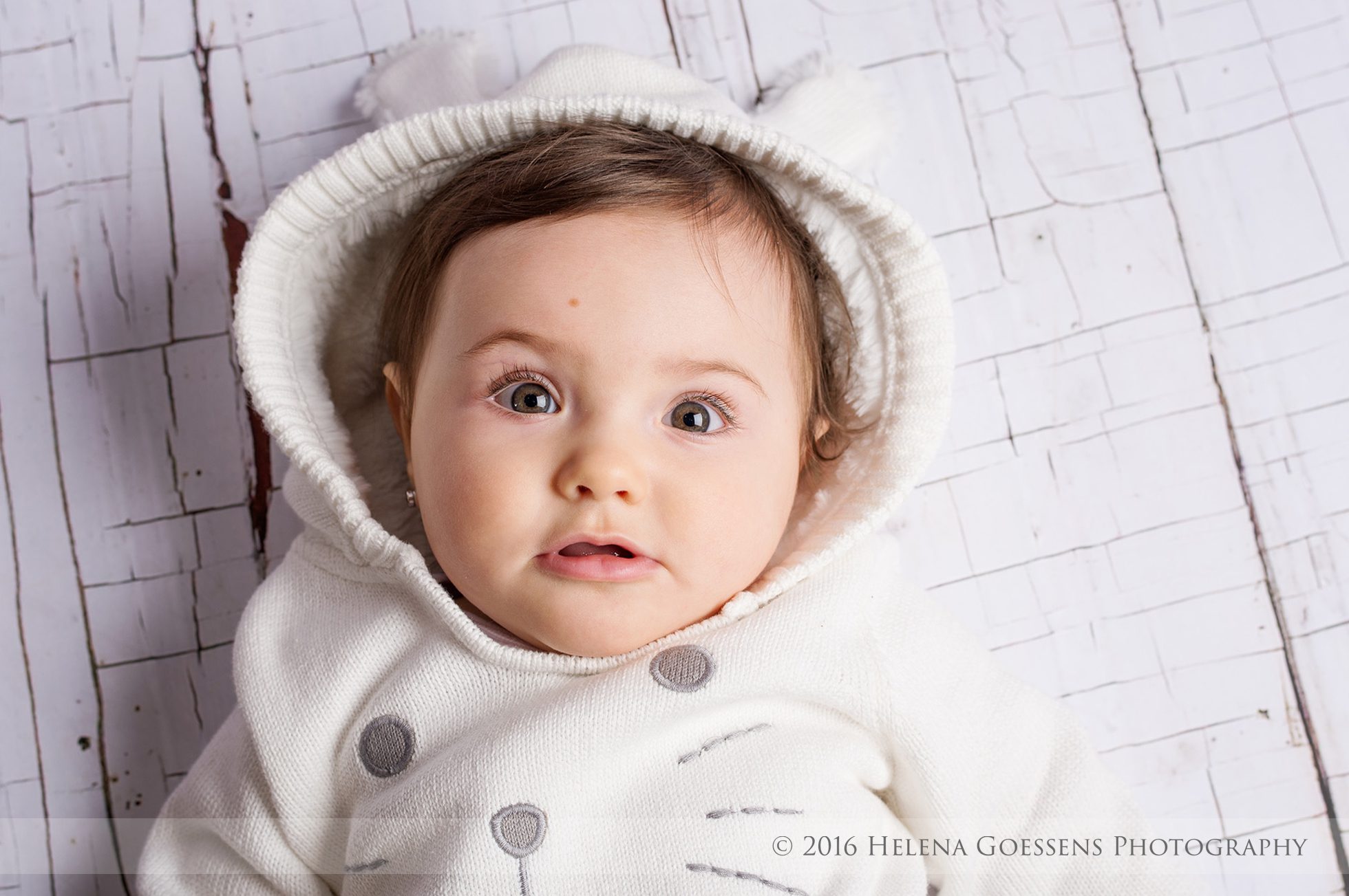 Baby in white outfit with big green eyes
