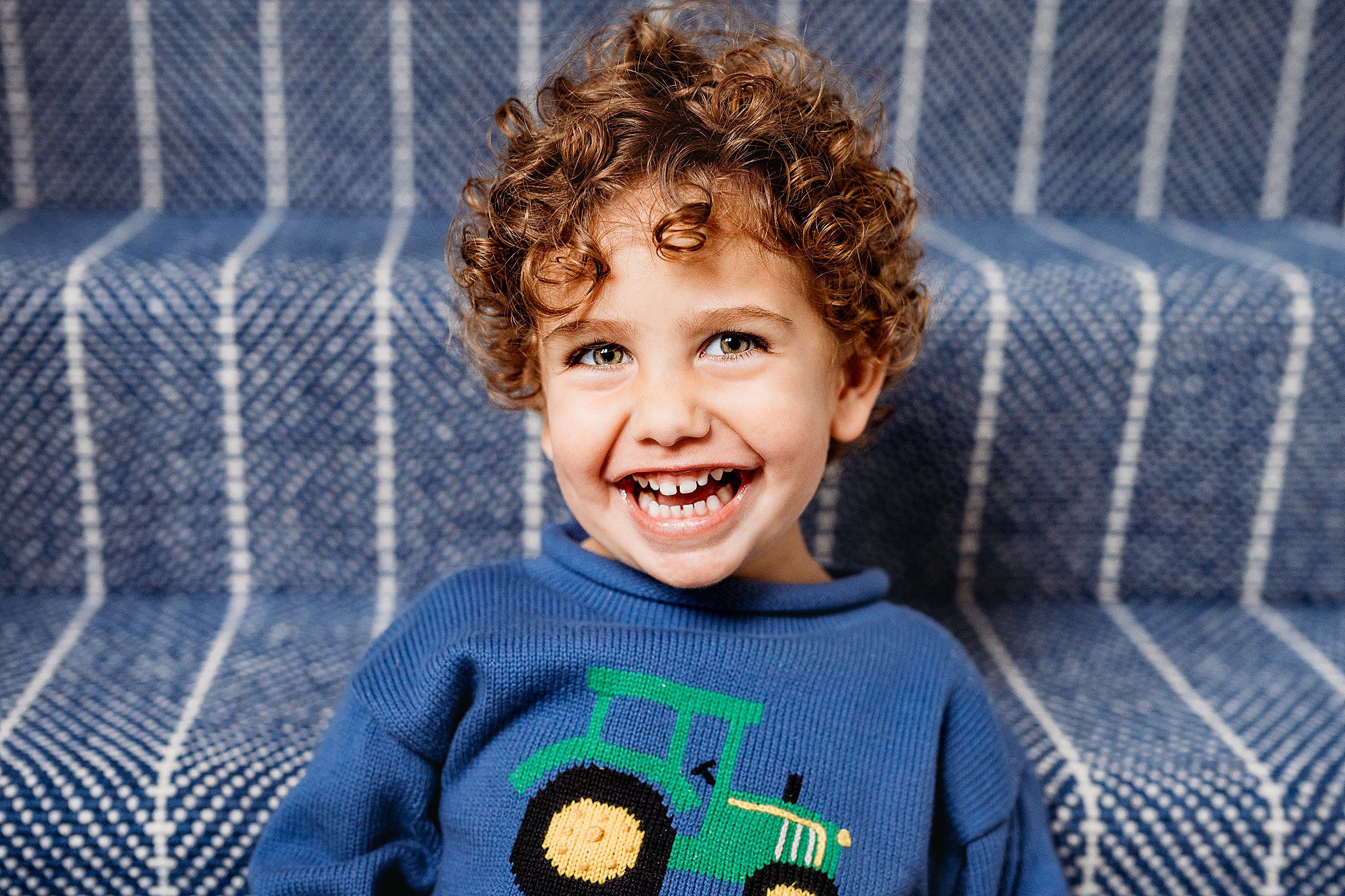 Boy with green eyes smiling - wearing a blue sweater - Boston Newborn and Family Photographer Helena Goessens Photography