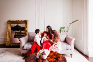 Mom in a red dress and 3 kids sitting on a sofa