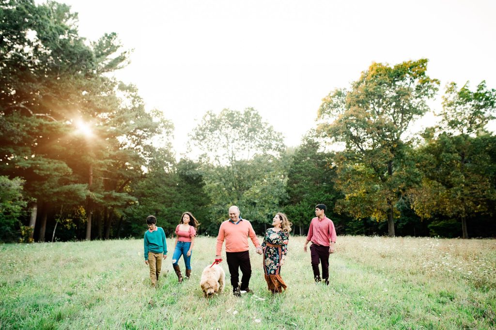 family of five walks with dog in field during family portraits with Helena Goessens Photography