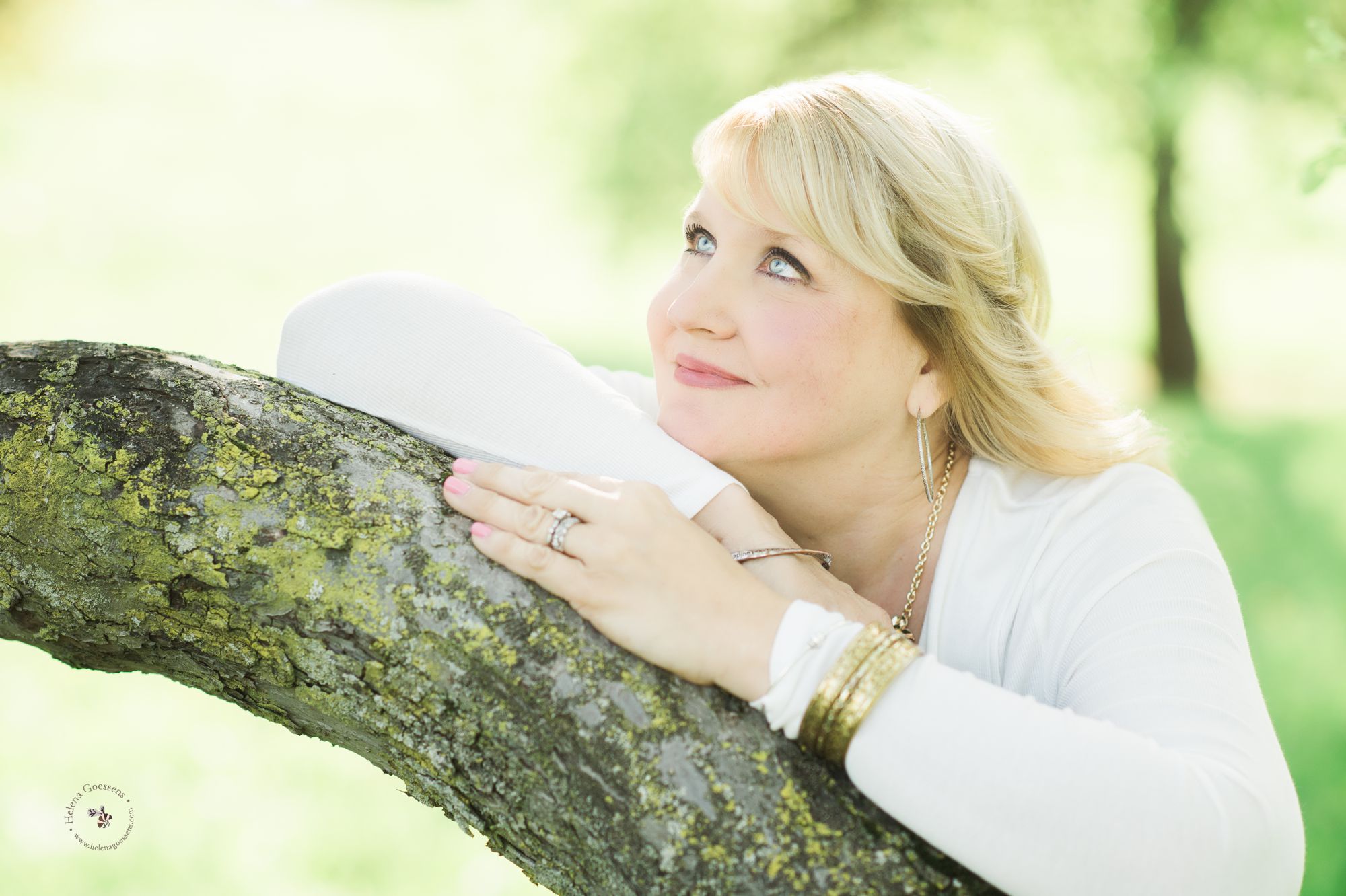 blond woman with blue eyes and white top on a tree branch