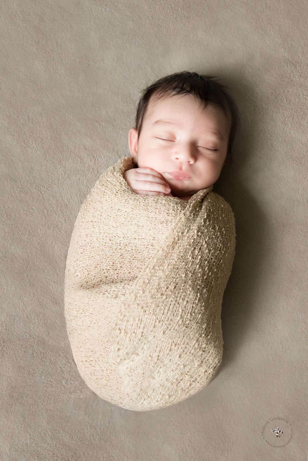 newborn wrapped in a beige wrap