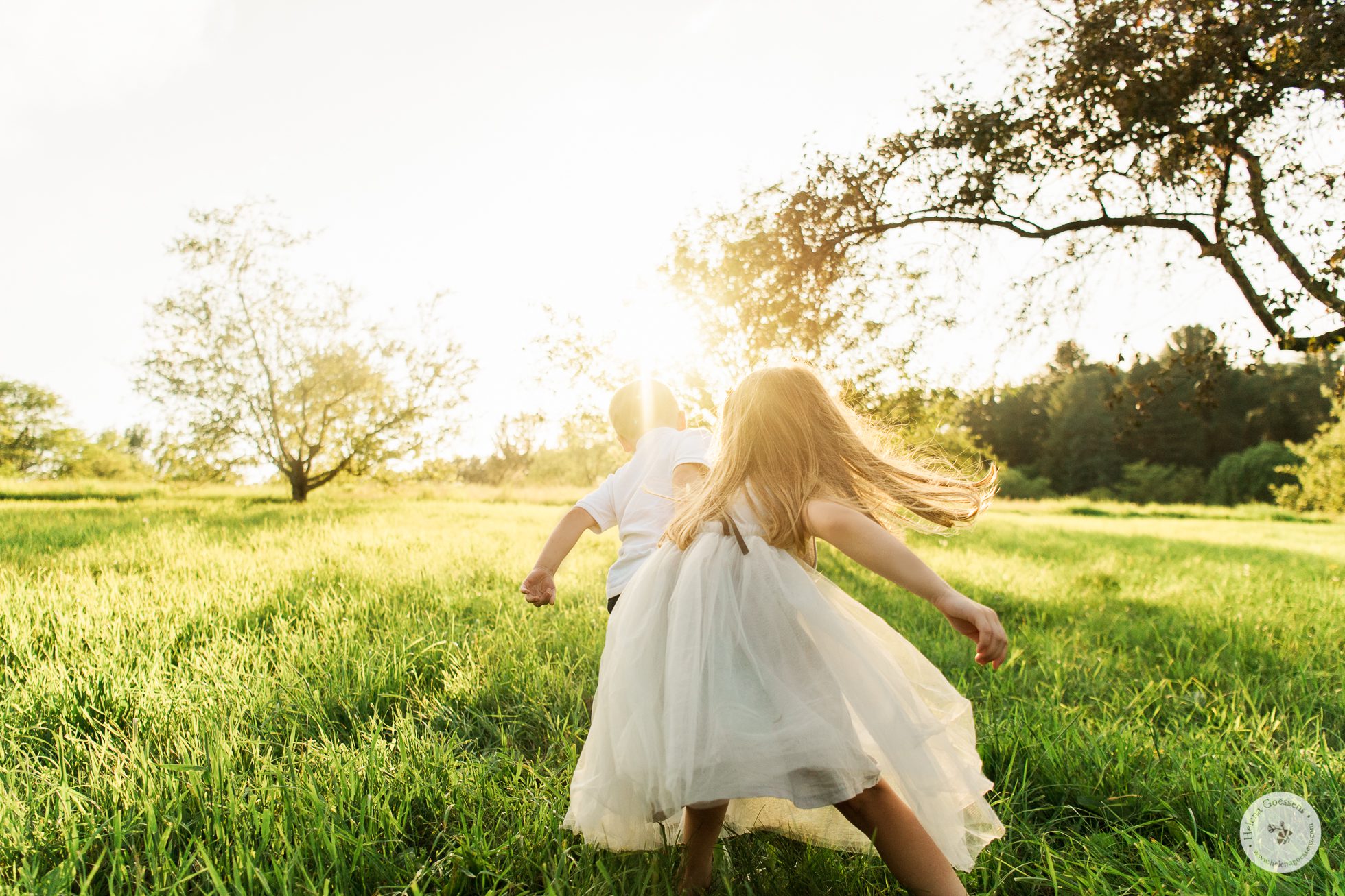 kids playing in a green field at sunset. Image by Helena goessens Photography.
