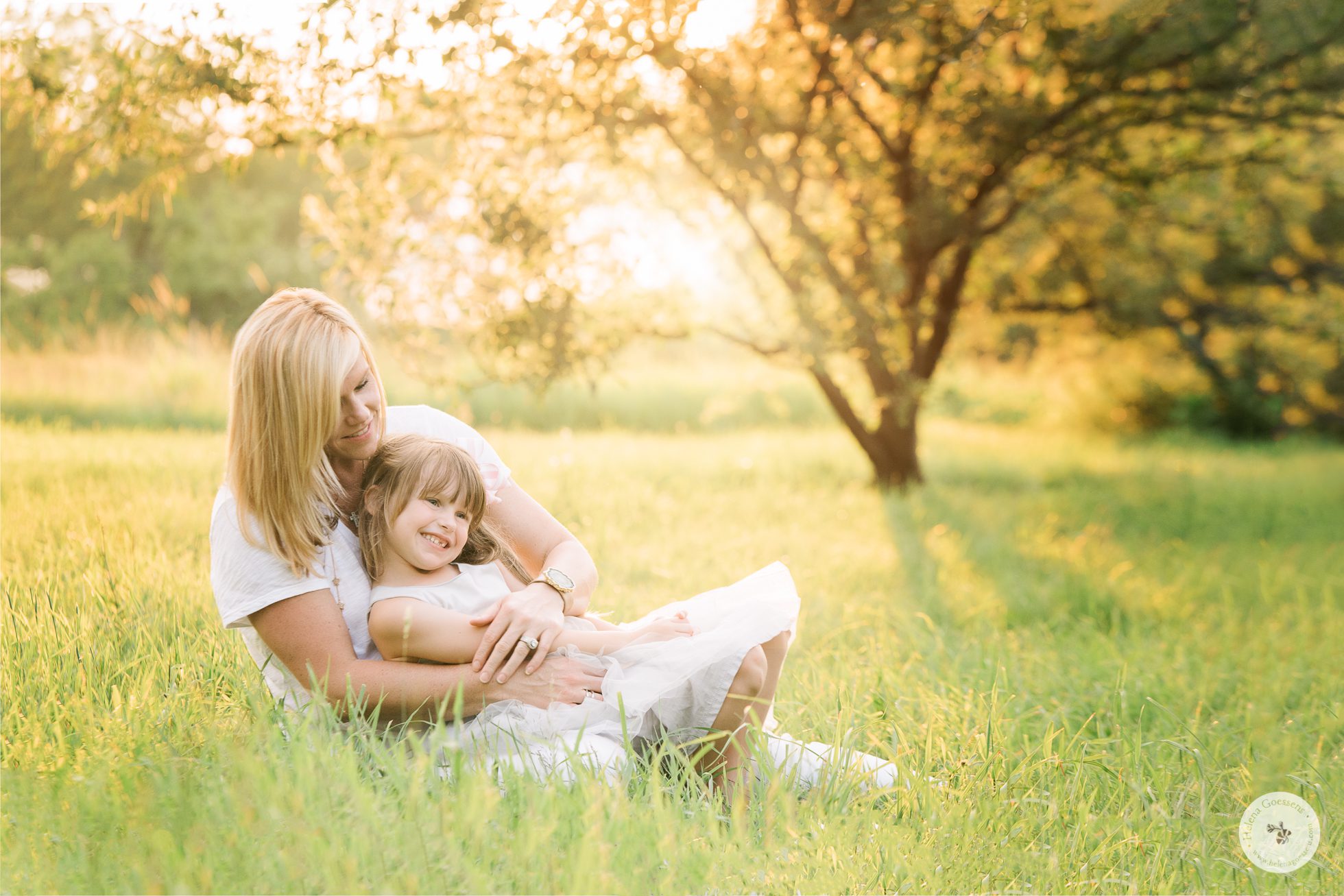 Mom and daughter sitting on the grass in a summer late afternoon. Image by Helena Goessens Photography.