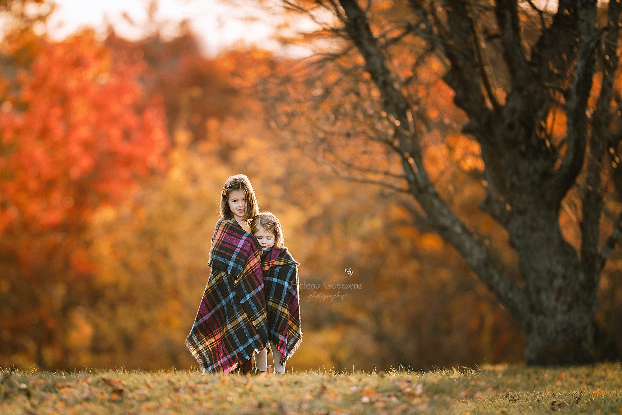 sisters cuddle in flannel blanket during family portraits with Helena Goessens