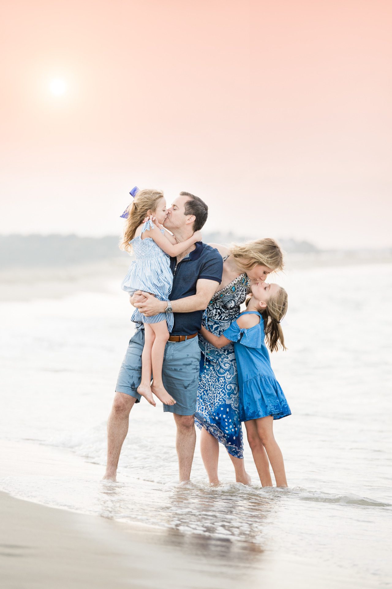 Family of four kissing at the beach