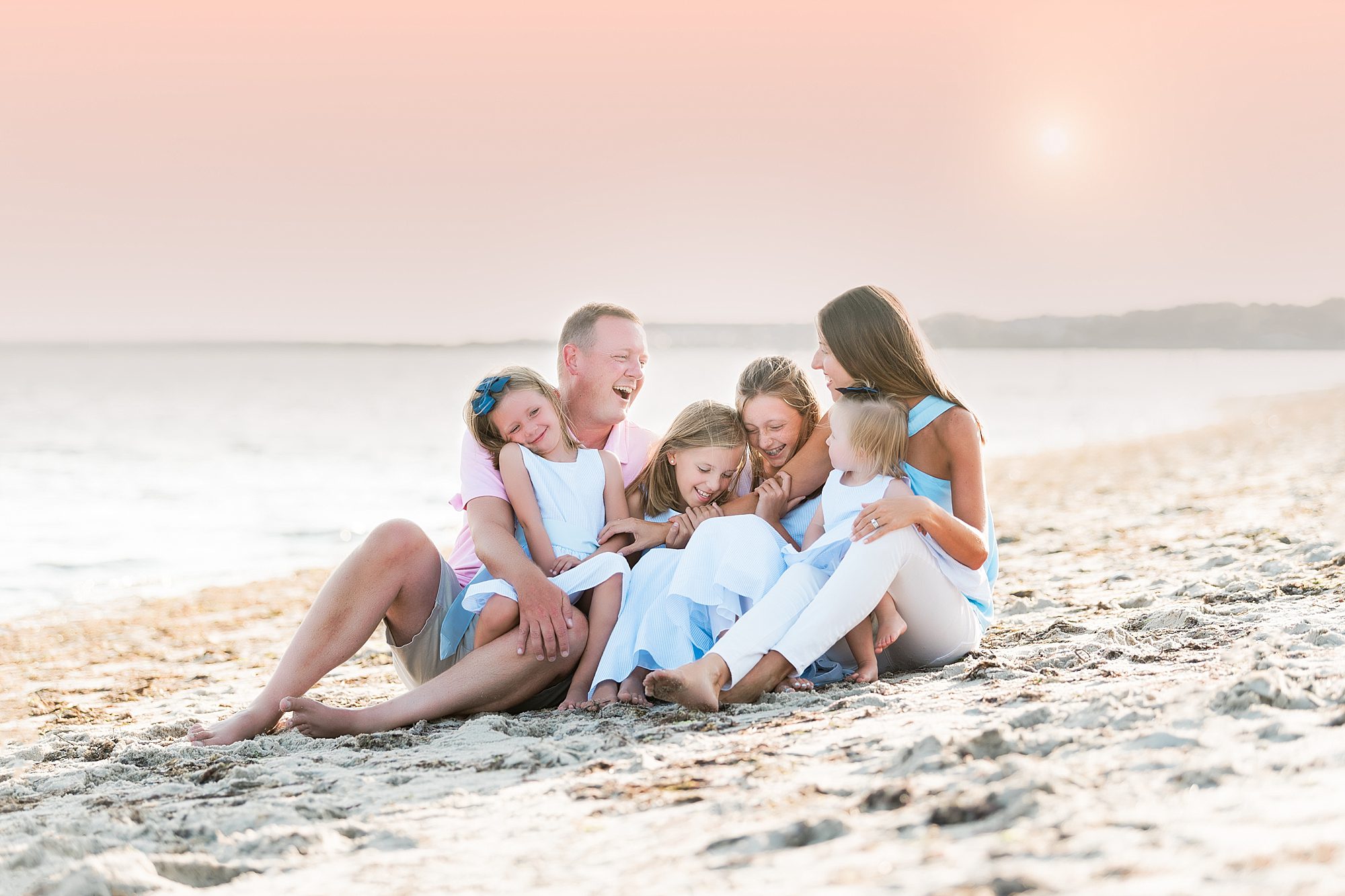 Family of 6 laughing and hugging at the beach