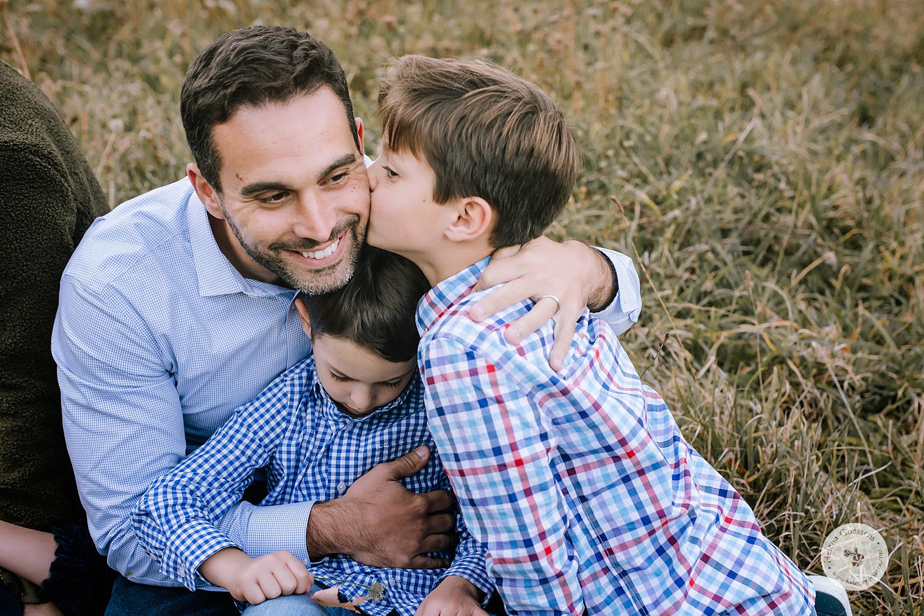 boys sit with dad during family photos by Helena Goessens Photography