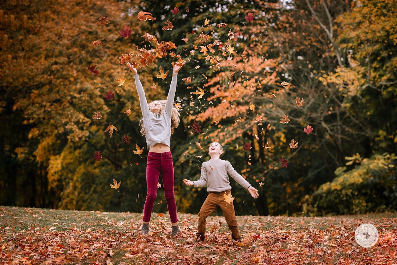 kids play in leaves during family portraits with Helena Goessens Photography