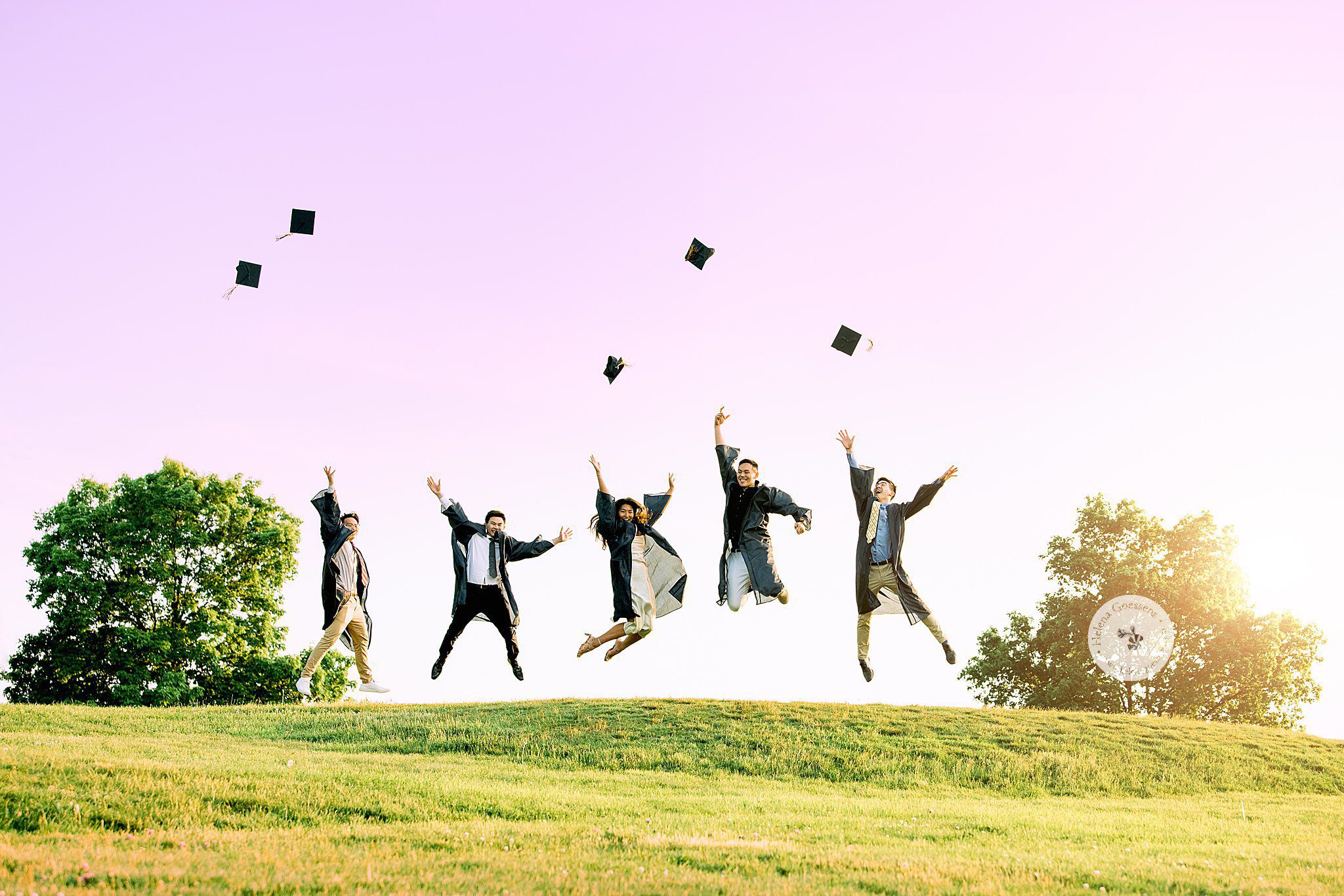 seniors jump and throw caps during senior portraits by Helena Goessens Photography