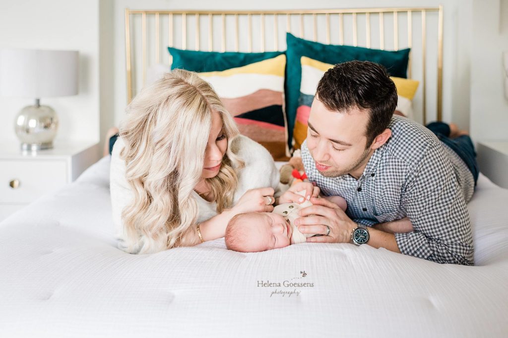 Helena Goessens Photography photographs new parents looking at baby on bed