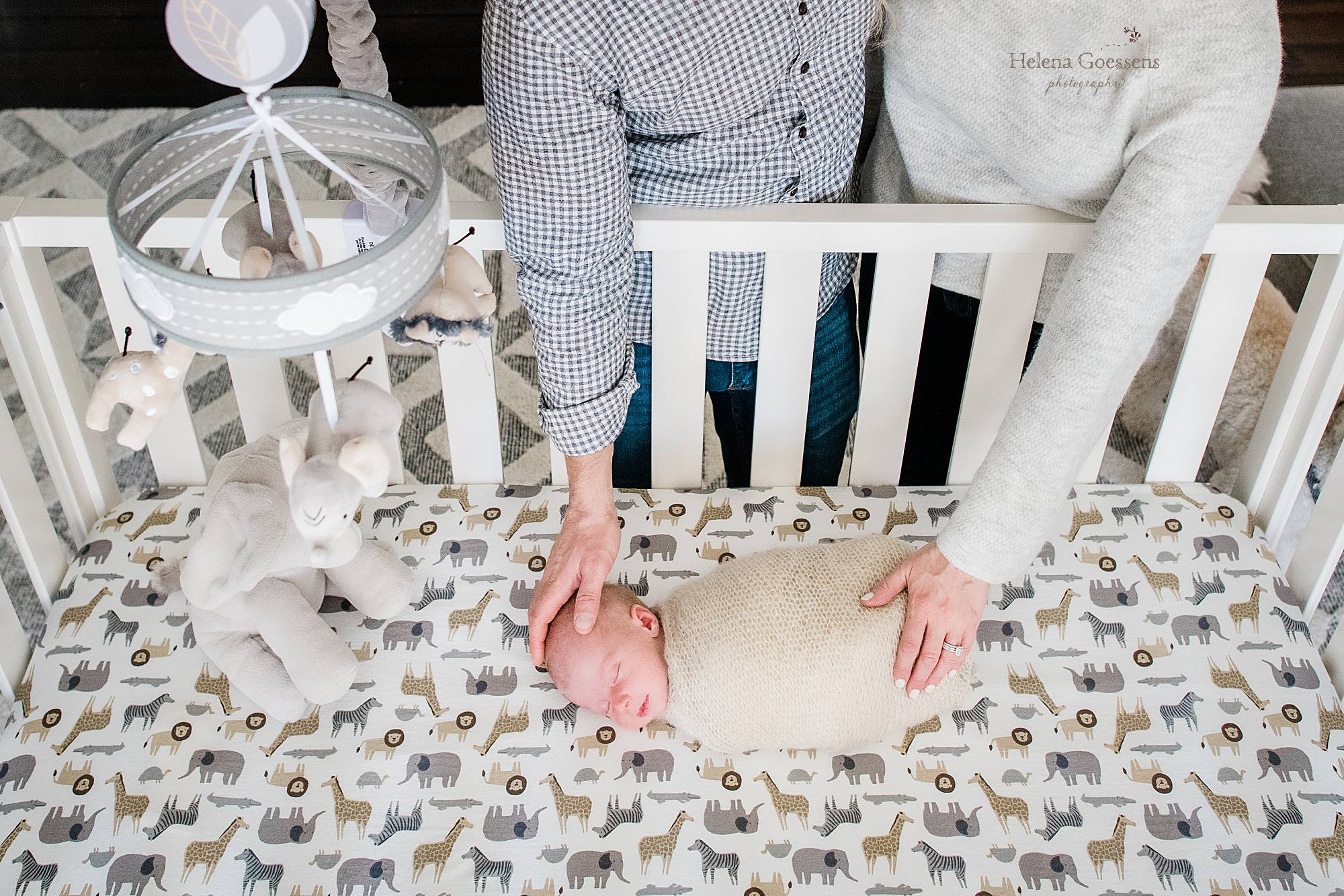 mom and dad hold newborn baby boy in crib photographed by Helena Goessens Photography