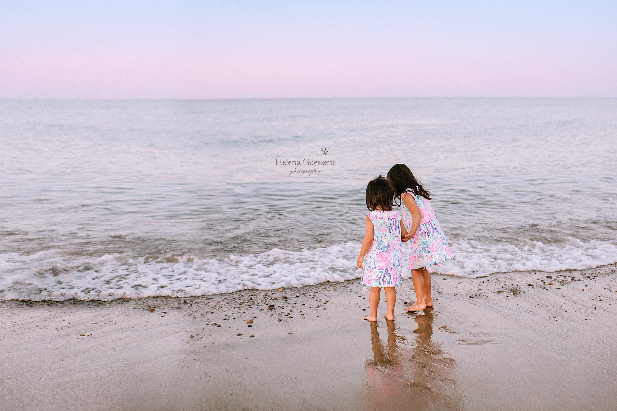 sisters play in water during beach family session with Helena Goessens Photography
