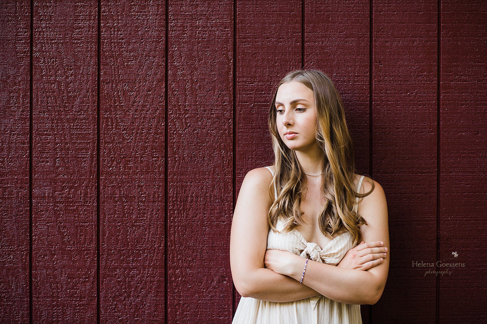 Helena Goessens Photography photographs high school senior by red wall at Bradley Estate