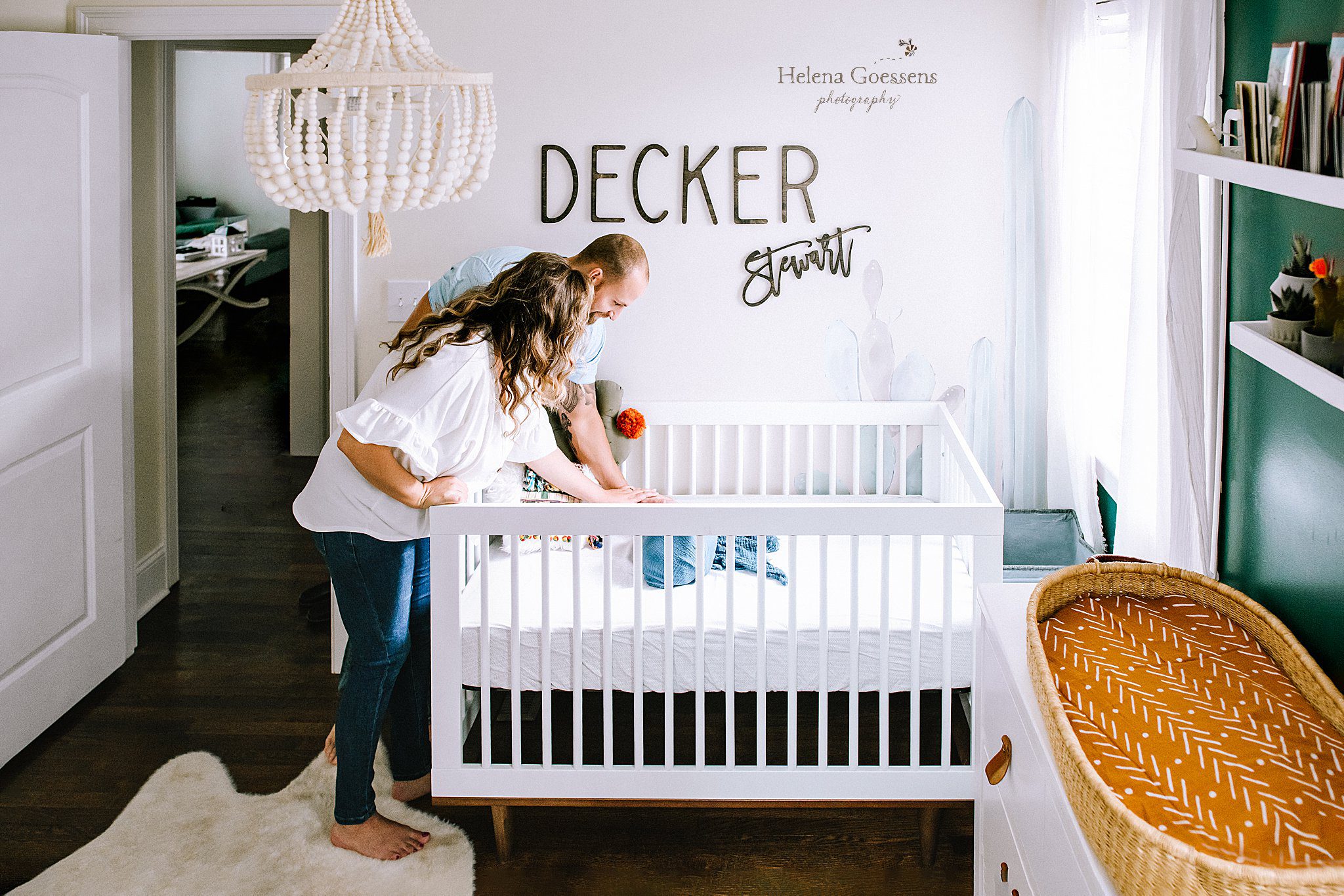 parents look over crib at newborn baby photographed by Helena Goessens Photography