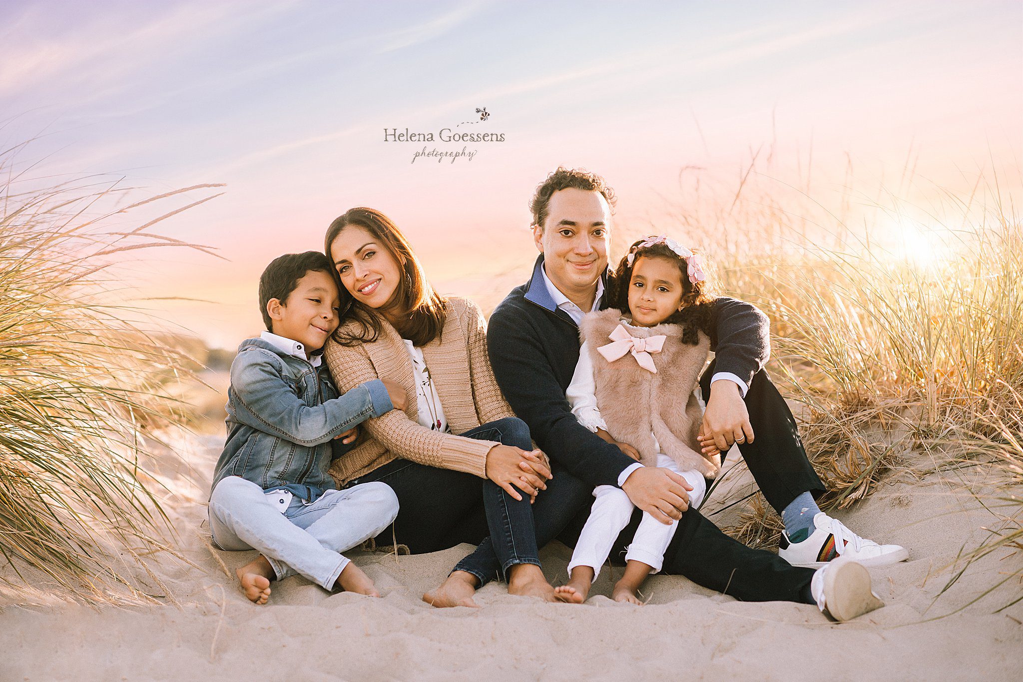 family of four sits on sand during family pictures with Helena Goessens Photography