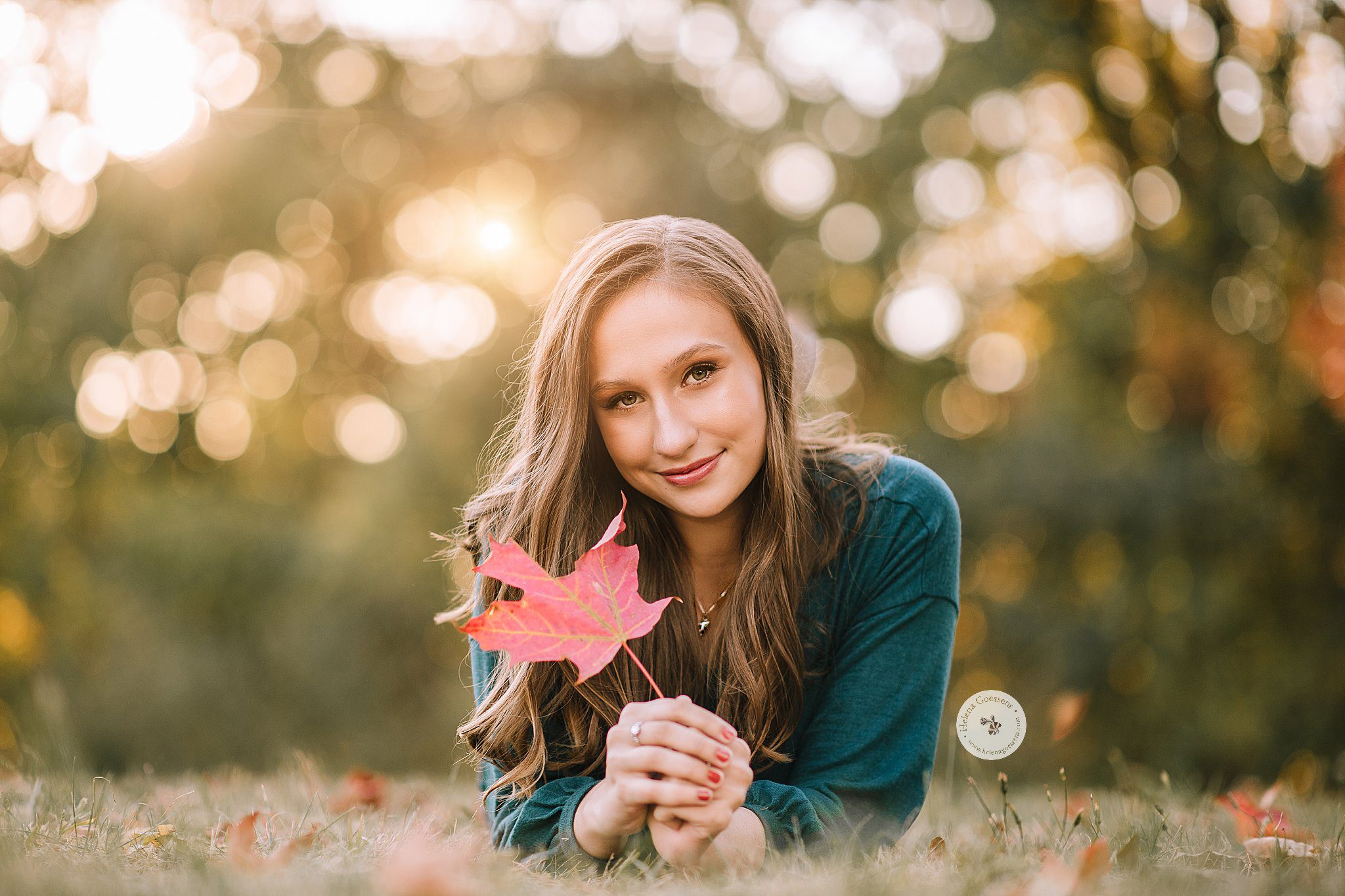 senior girl holds red maple leaf during Larz Anderson Park photos