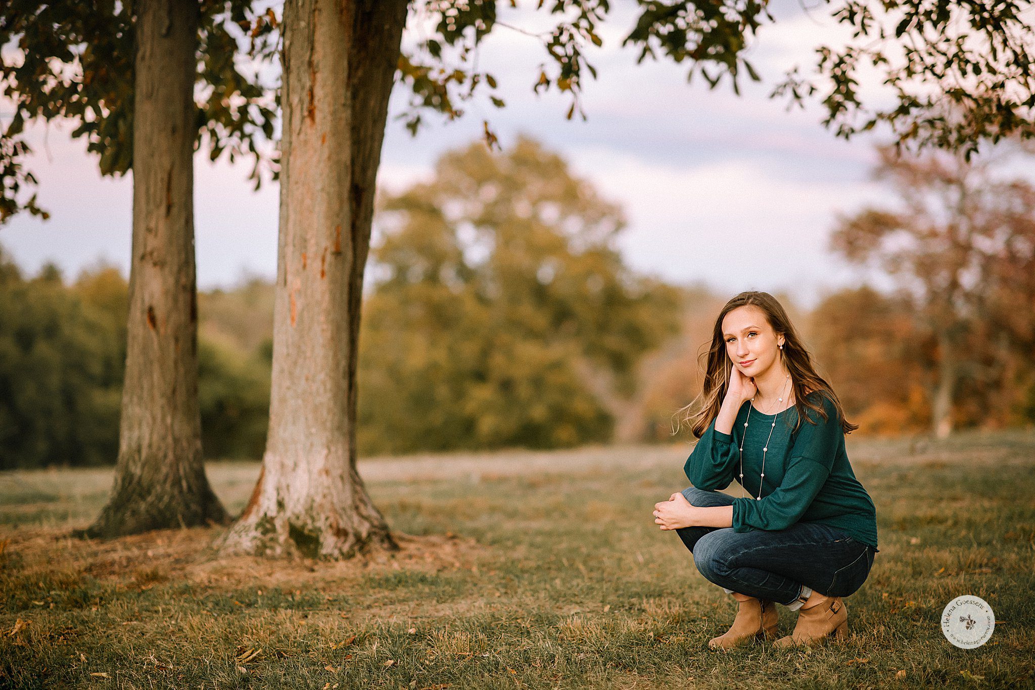 senior in emerald green sweater poses in Larz Anderson Park