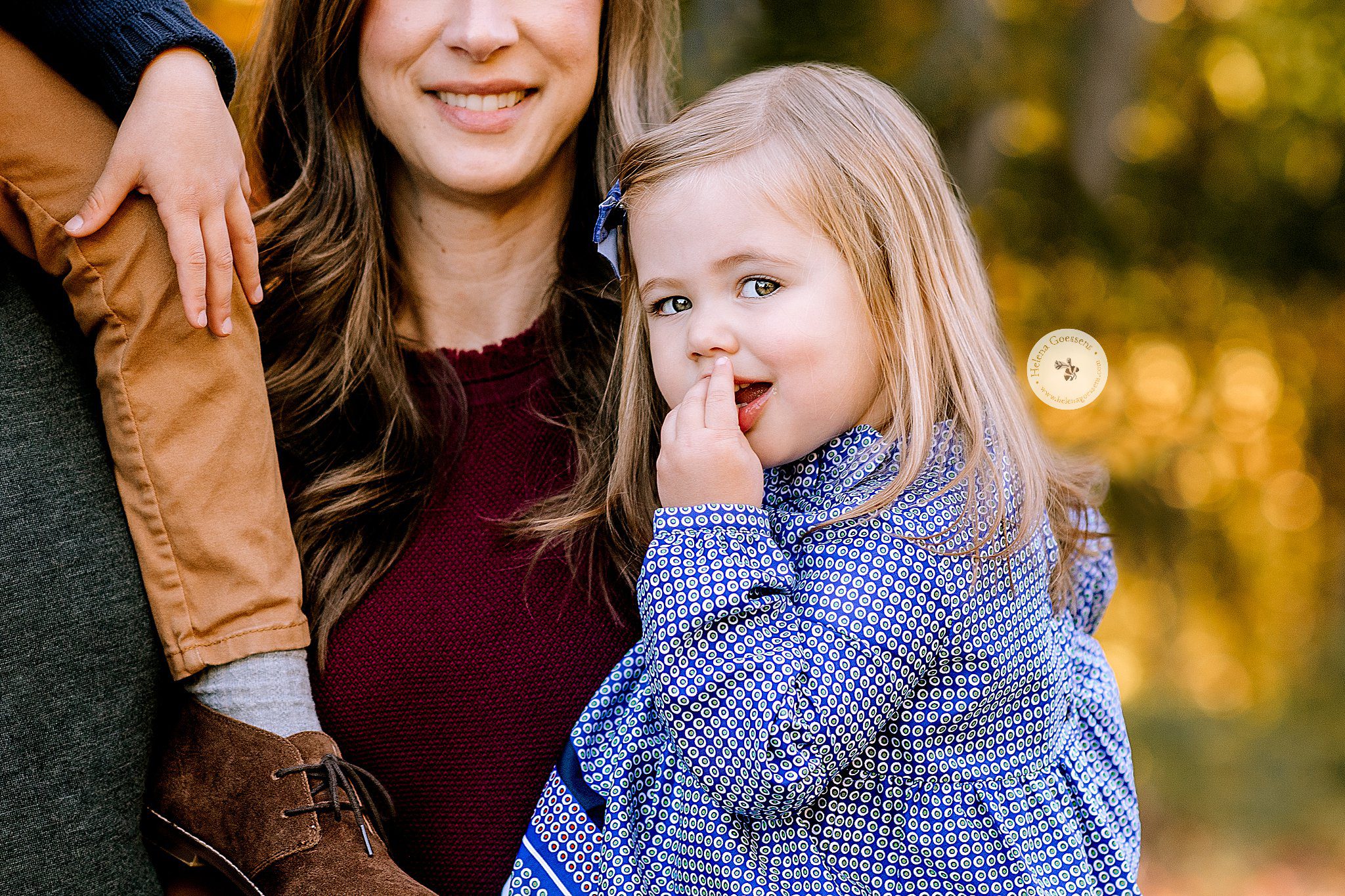 toddler smiles at camera under fingers during family photos 