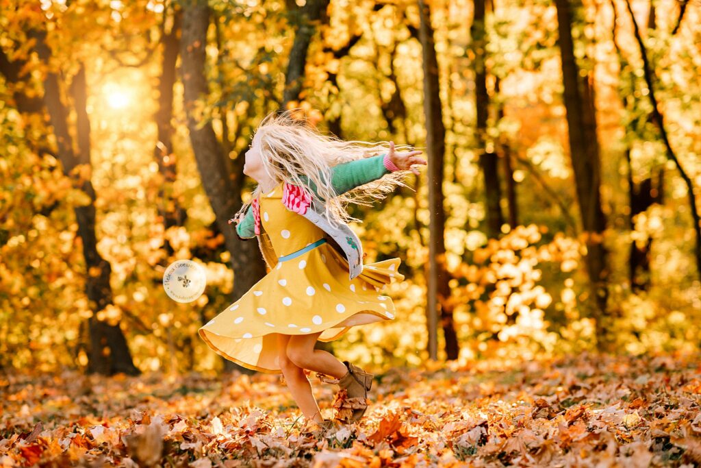 daughter spins around in leaves during Brookline MA family session