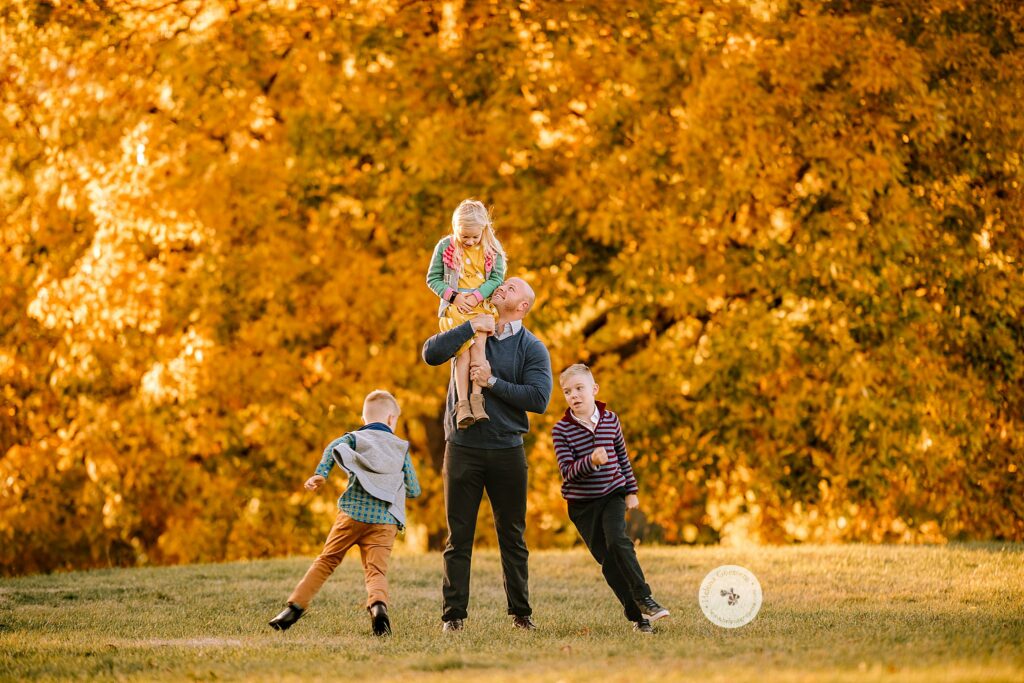 dad plays with kids during Fall Family Portraits in Brookline MA