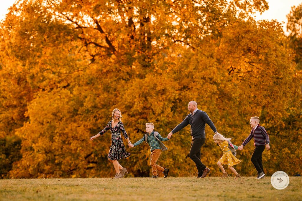 Helena Goessens Photography photographs family running through park during Fall Family Portraits in Brookline MA