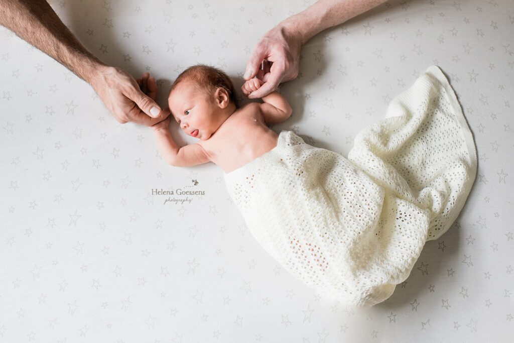 Helena Goessens Photography photographs baby on sheet holding dad's hands
