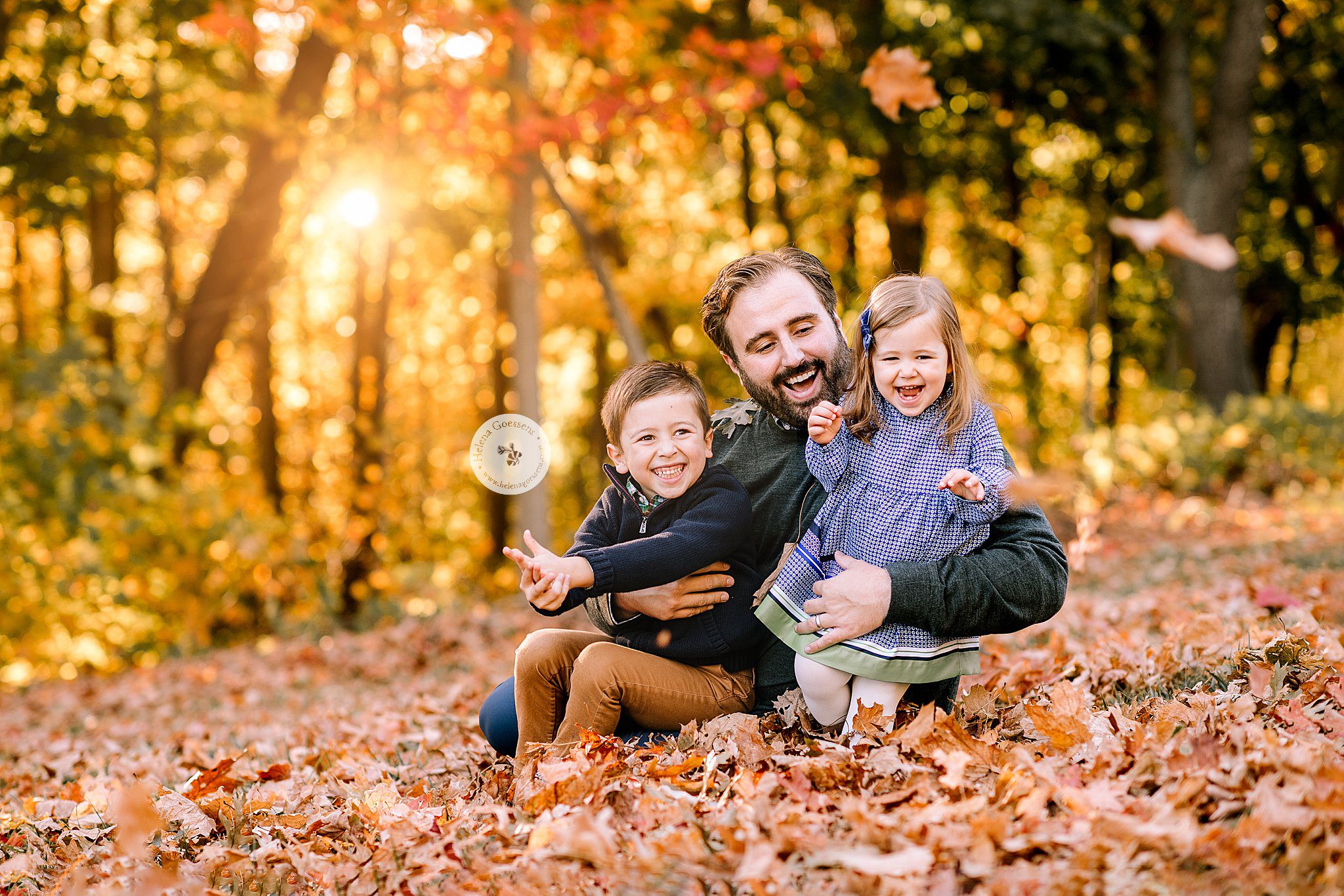 dad plays with kids in leaves during Larz Anderson Park family photos