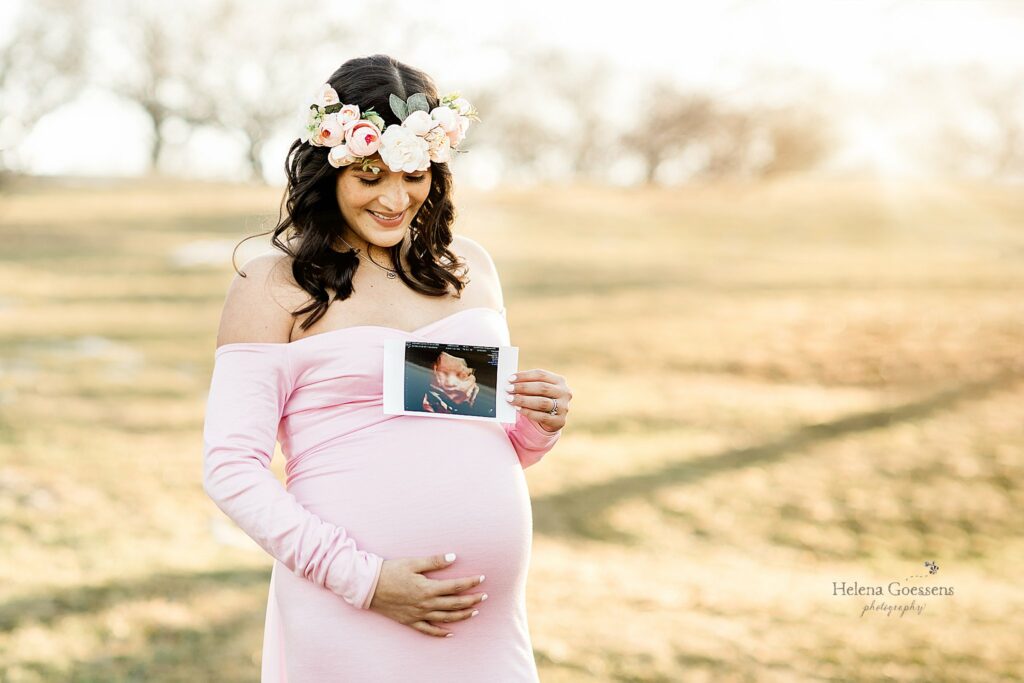 mom in pink gown holding ultrasound picture at arnold's arboretum maternity session