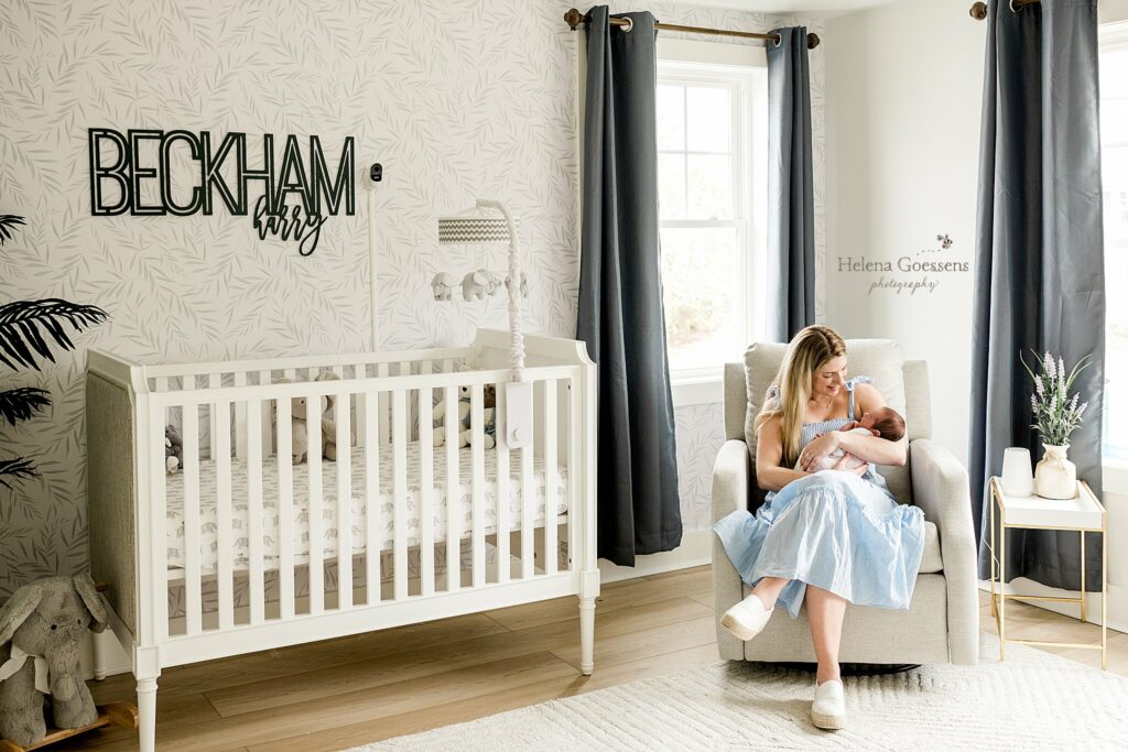 mom rocks baby boy by crib at home during lifestyle newborn session 