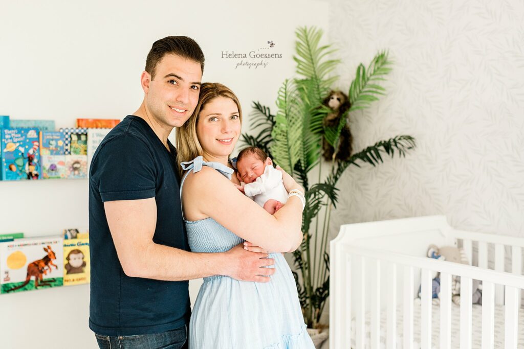 new parents hold baby boy in jungle themed nursery 