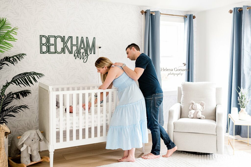 new parents look at baby boy in white crib during lifestyle newborn photos 