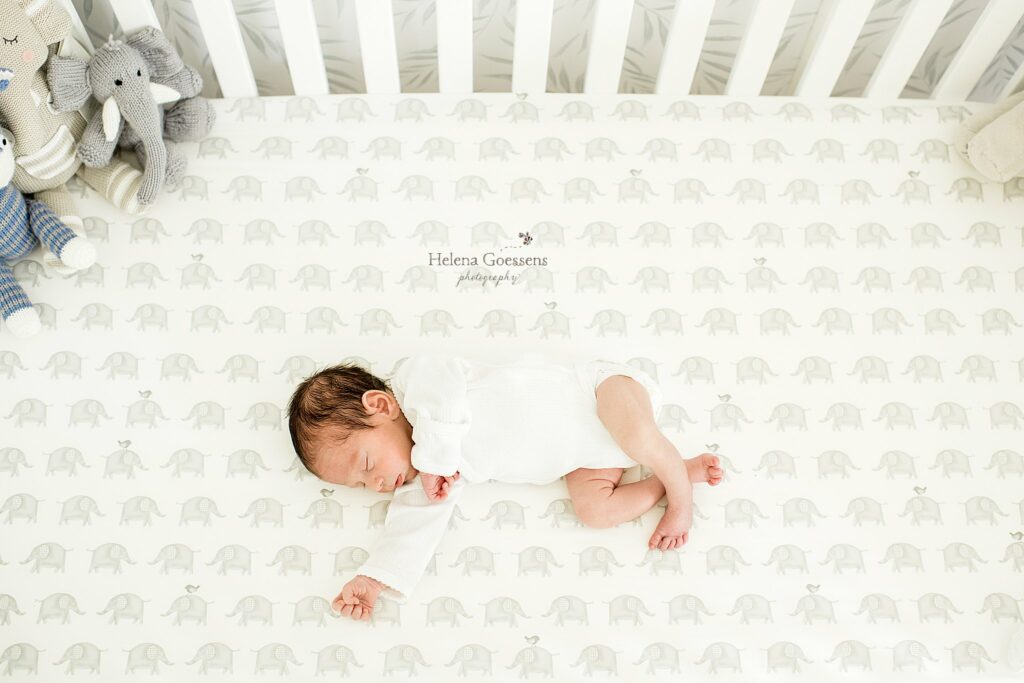 new baby boy lays in crib during lifestyle newborn photos at home 