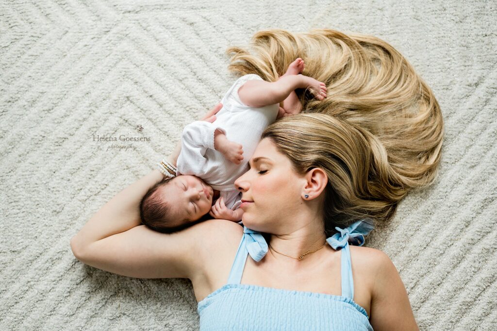 mom lays on nursery floor with baby boy on shoulder 