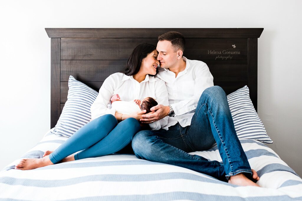 parents sit with new baby on bed at home during Boston lifestyle newborn session 
