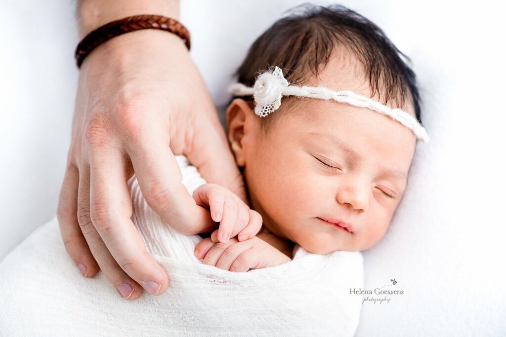 dad holds baby's hand during newborn photos at home