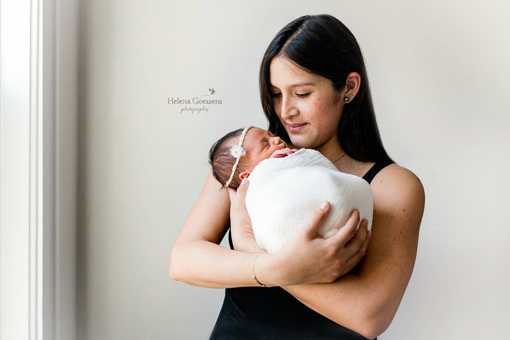 mom in black tank top holds baby girl in white wrap during Jamaica Plains lifestyle newborn session 