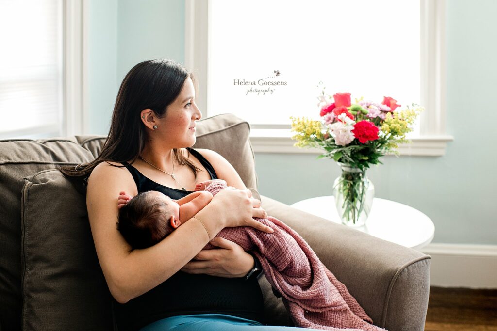 mom snuggles new baby girl in nursery during newborn photos at home 