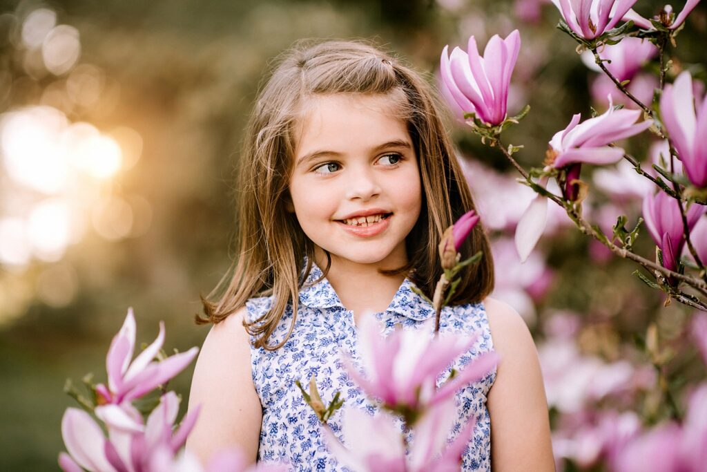 young girl hides in crabapple tree blossoms during spring family photos in MA