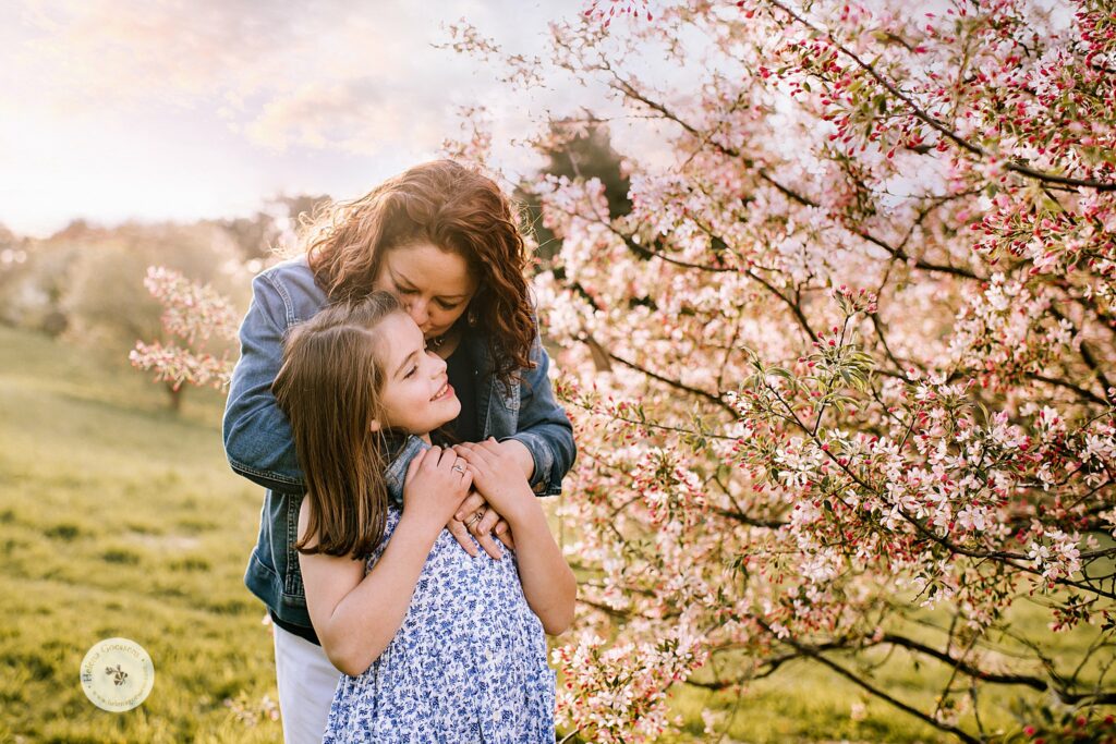 mom hugs daughter by crabapple tree during Peter's Hill family photos