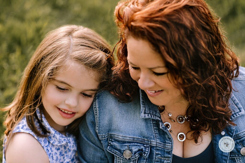 young daughter leans on mom's shoulder during spring family photos in Boston MA