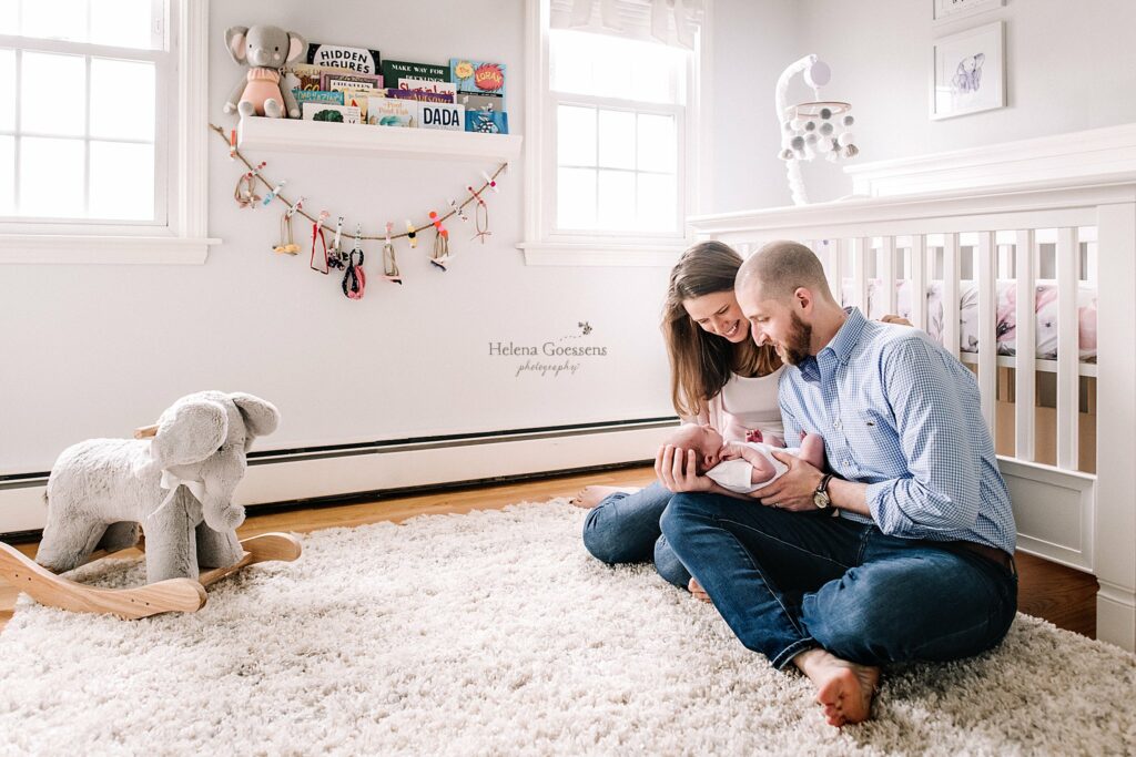 new parents sit by crib at home during Lifestyle Newborn Session in Quincy MA