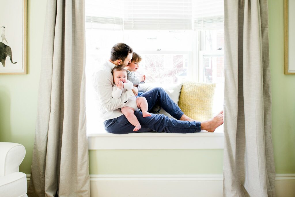 dad sits with sons in window seat of home in Weston MA 