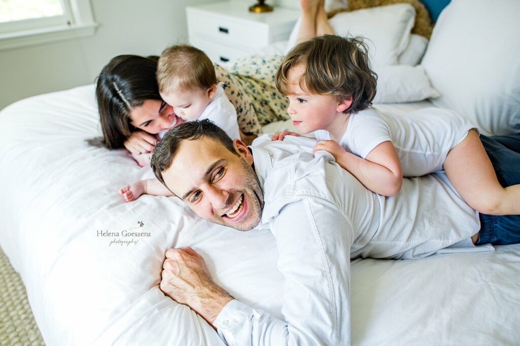 parents play with two sons on bed during MA family photos at home 