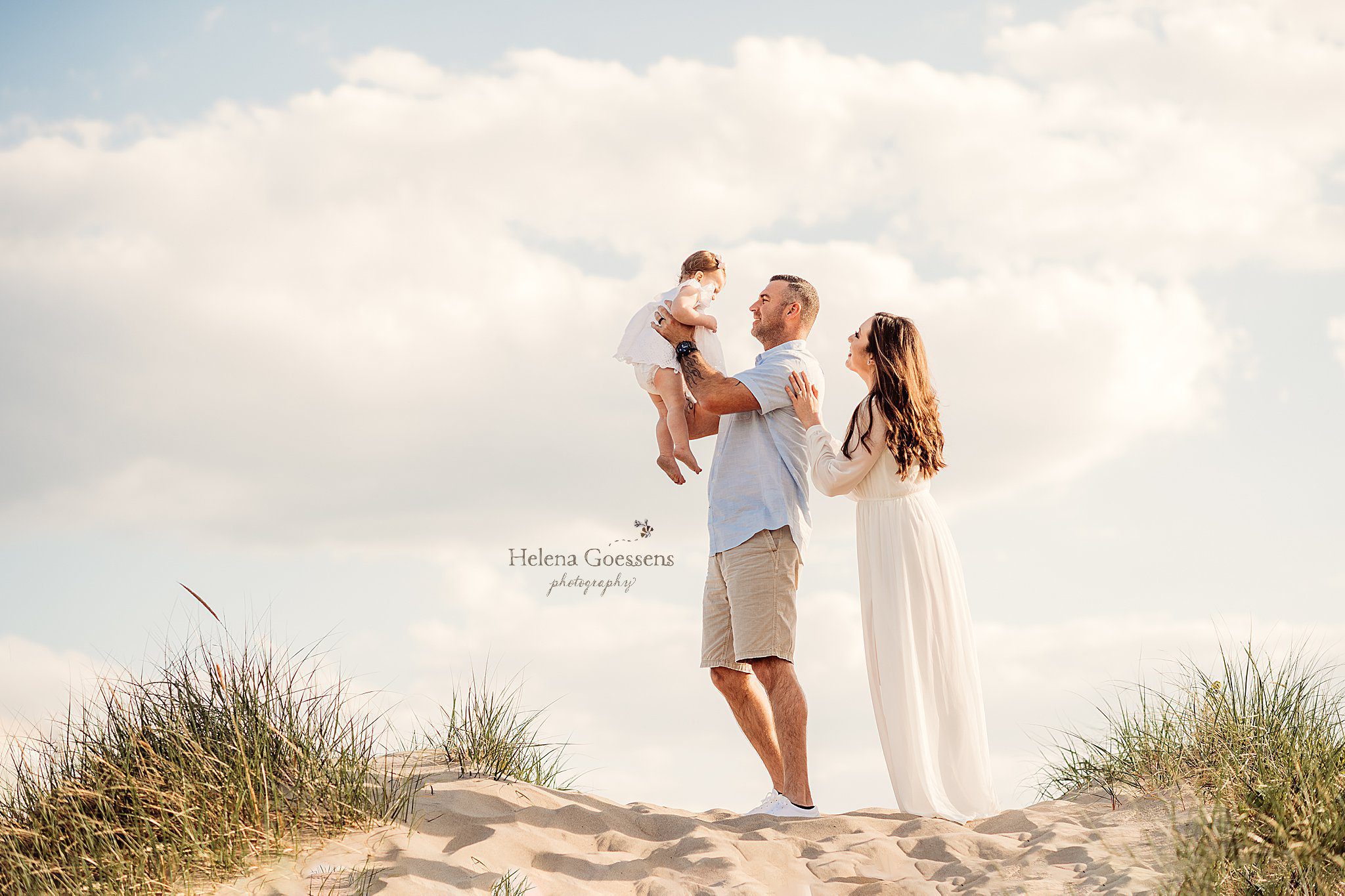 dad lifts up daughter with mom looking over shoulder during Rexhame Beach family session